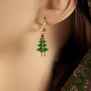 Peut inclure: Une paire de boucles d'oreilles en or avec un motif de sapin de No&euml;l vert et rouge.