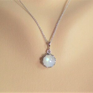 May include: A silver chain necklace with a round, iridescent moonstone pendant set in a silver bezel.