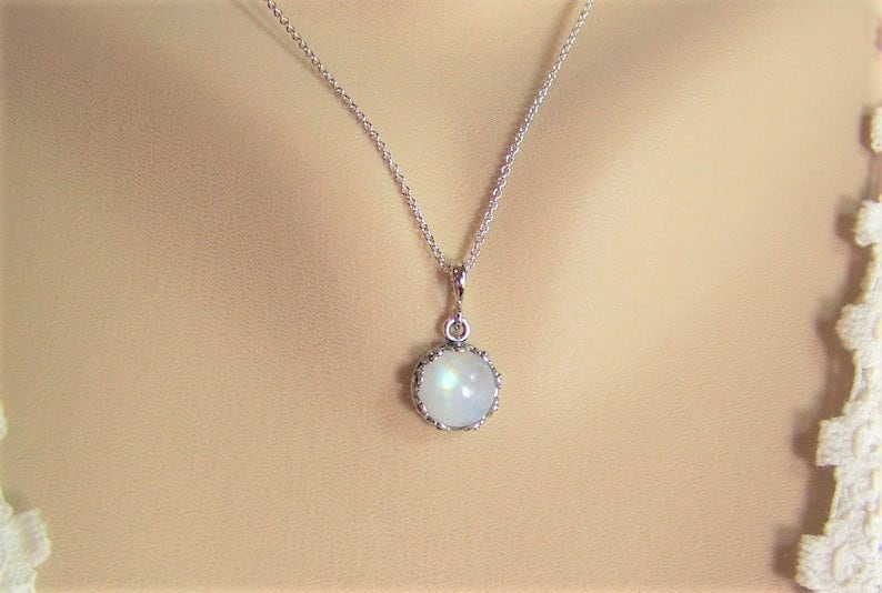 May include: A silver chain necklace with a round, iridescent moonstone pendant set in a silver bezel.