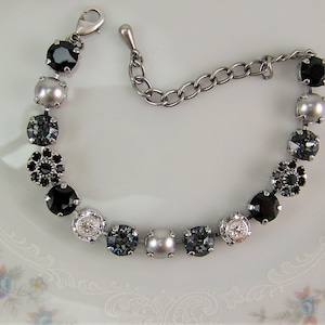 Puede incluir: Una pulsera de tono plateado que presenta una secuencia de cristales negros redondos, perlas grises, piedras facetadas de color gris oscuro y cristales transparentes. Incluye una cadena de extensi&oacute;n met&aacute;lica y un cierre de mosquet&oacute;n.