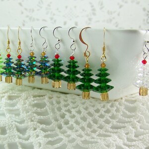 Peut inclure: Dix paires de boucles d'oreilles en cristal en forme de sapin de No&euml;l. Les boucles d'oreilles sont faites de cristaux transparents, verts et bleus et sont enfil&eacute;es sur des fils d'or et d'argent. Les boucles d'oreilles sont toutes de designs diff&eacute;rents, mais elles pr&eacute;sentent toutes une forme de sapin de No&euml;l.