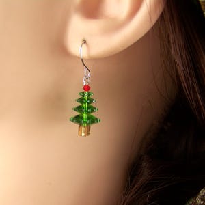 Peut inclure: Boucles d'oreilles en forme de sapin de No&euml;l en cristal vert avec un cristal rouge au sommet et une perle dor&eacute;e en bas.