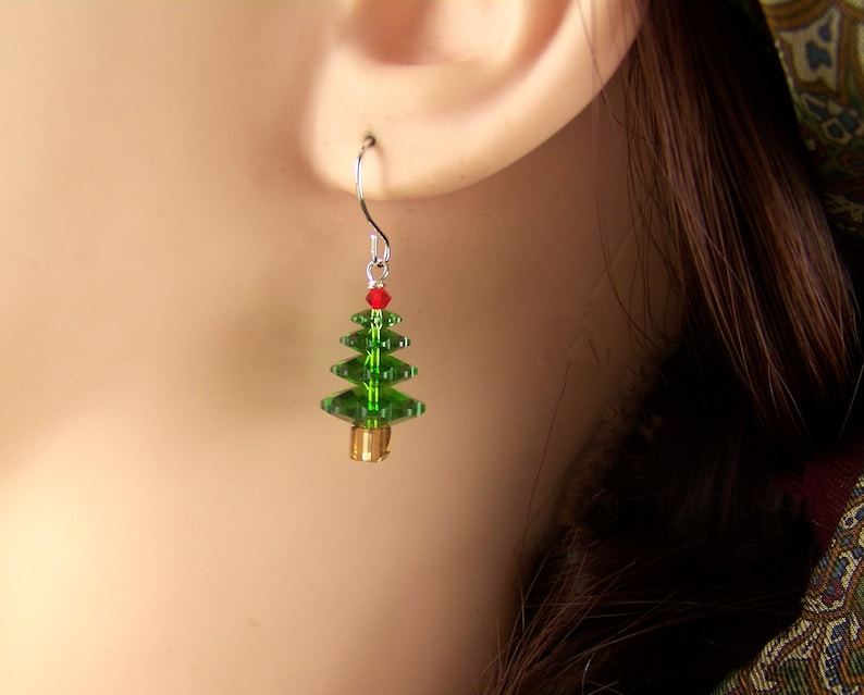 Peut inclure: Boucles d'oreilles en forme de sapin de No&euml;l en cristal vert avec un cristal rouge au sommet et une perle dor&eacute;e en bas.