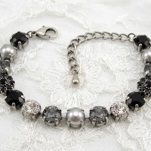 Puede incluir: Una pulsera de tono plateado que presenta una secuencia de cristales facetados en negro, gris y transparente, intercalados con perlas grises lisas. Incluye un cierre de mosquet&oacute;n y una cadena de extensi&oacute;n ajustable con un peque&ntilde;o dije.
