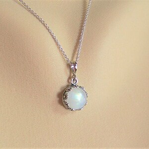 May include: A silver chain necklace with a round, white moonstone pendant set in a silver bezel.