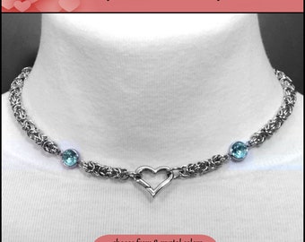 Puede incluir: Un collar de cadena de plata con un cierre en forma de corazón y dos acentos de cristal azul claro. El texto "Fiery Passion Discreet Day Collar" está en la parte superior de la imagen. El texto "elige entre 8 colores de cristal, a medida para que te quede perfecto" está en la parte inferior de la imagen.