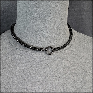 May include: Black braided chain choker necklace with a black metal ring clasp.
