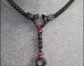 May include: Black metal necklace with a dragon head design and a dangling ring. The necklace has red accents.