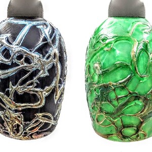 K&ouml;nnte beinhalten: Vier dekorative Glasflaschen mit einem einzigartigen, filigranen, netzartigen Design. Die Flaschen sind in Blaut&ouml;nen, Schwarz, Gr&uuml;n und Braun.