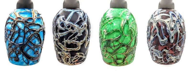 K&ouml;nnte beinhalten: Vier dekorative Glasflaschen mit einem einzigartigen, filigranen, netzartigen Design. Die Flaschen sind in Blaut&ouml;nen, Schwarz, Gr&uuml;n und Braun.