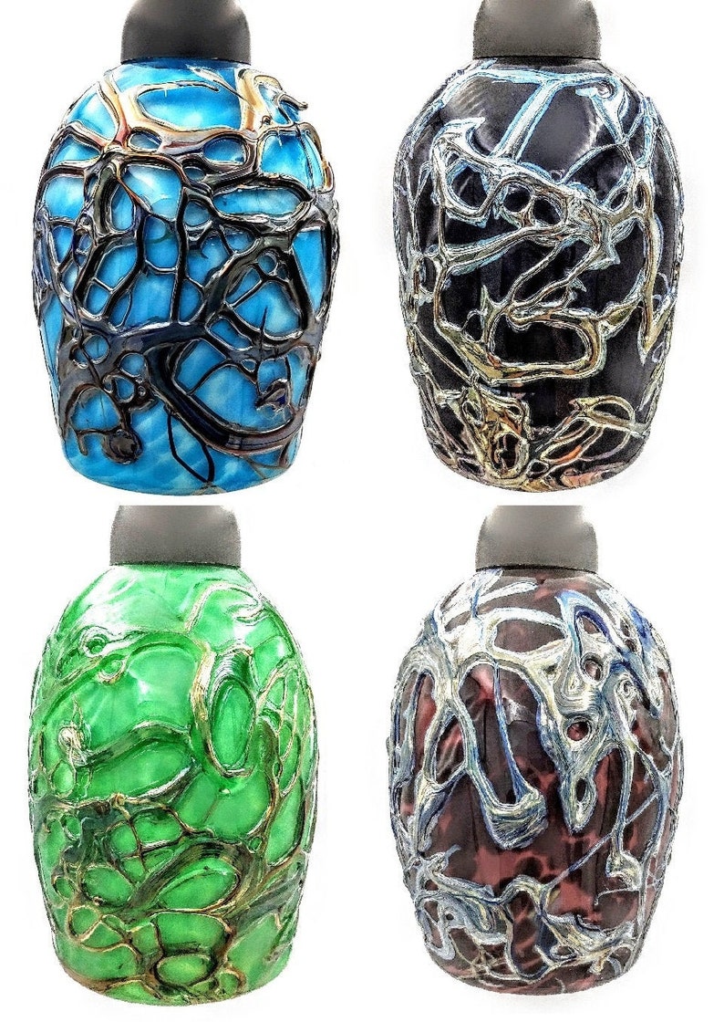 K&ouml;nnte beinhalten: Vier Glasflaschen mit einem einzigartigen, komplizierten Design. Jede Flasche hat eine andere Grundfarbe mit einem silbernen, metallischen, netzartigen Muster.
