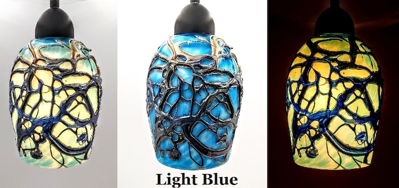 K&ouml;nnte beinhalten: Eine Glaspendelleuchte mit einem blauen und gelben Buntglasdesign. Das Glas hat ein schwarzes, netzartiges Muster. Die Leuchte ist ein- und ausgeschaltet dargestellt.