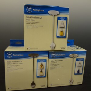 K&ouml;nnte beinhalten: Drei Westinghouse Mini-Pendelleuchten-Sets in den Ausf&uuml;hrungen Wei&szlig;, &Ouml;l-Bronze und Nickel. Jedes Set enth&auml;lt ein 127 cm langes Kabel, einen 12,7 cm gro&szlig;en Baldachin und einen Glasschirm. Die Sets sind in Kartons mit Produktinformationen und Modellnummern verpackt.