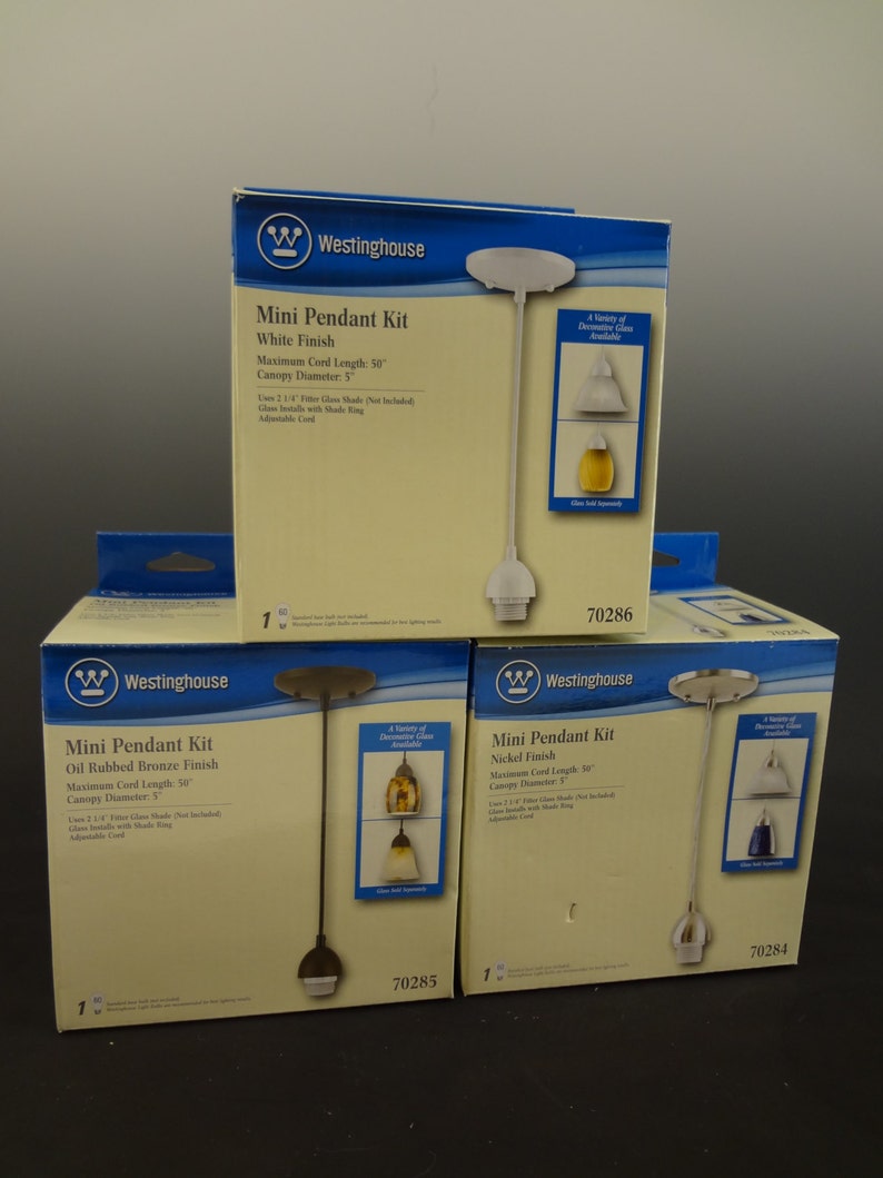 K&ouml;nnte beinhalten: Drei Westinghouse Mini-Pendelleuchten-Sets in den Ausf&uuml;hrungen Wei&szlig;, &Ouml;l-Bronze und Nickel. Jedes Set enth&auml;lt ein 127 cm langes Kabel, einen 12,7 cm gro&szlig;en Baldachin und einen Glasschirm. Die Sets sind in Kartons mit Produktinformationen und Modellnummern verpackt.
