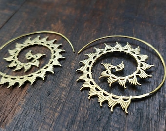 May include: A pair of gold-toned spiral hoop earrings with a delicate, intricate design. The earrings are made of metal and have a circular shape.