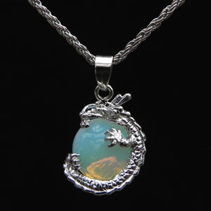 May include: A silver dragon pendant necklace featuring a round, light blue opal gemstone in the centre. The dragon's tail wraps around the stone.
