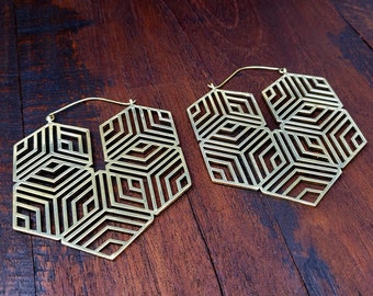Peut inclure: Une paire de grandes boucles d'oreilles créoles dorées avec un motif géométrique en forme de nid d'abeille. Les boucles d'oreilles sont en métal et ont une finition brillante.