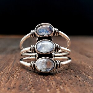 Pode incluir: Um anel de prata com tr&ecirc;s gemas de pedra da lua ovaladas engastadas em um design de banda tripla.