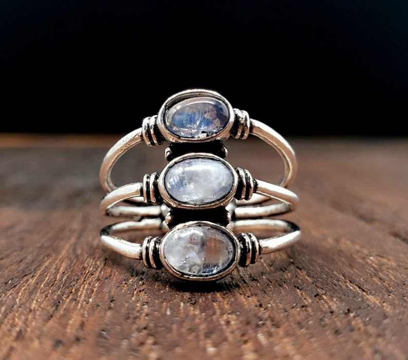 Pode incluir: Um anel de prata com tr&ecirc;s gemas de pedra da lua ovaladas engastadas em um design de banda tripla.