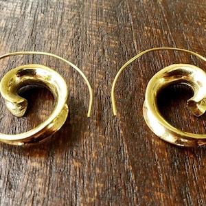 May include: A pair of gold-toned hoop earrings with a spiral design. The earrings are made of metal and have a simple, elegant look.