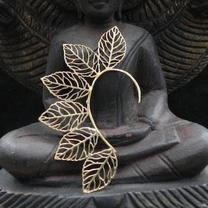 May include: Gold leaf ear cuff with a delicate, intricate design. The cuff is shaped like a crescent moon and features multiple leaves.