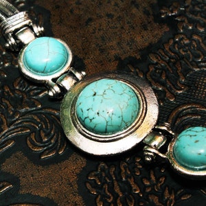 May include: A silver bracelet with three turquoise stones. The stones are set in silver bezels and the bracelet has a chain link design.
