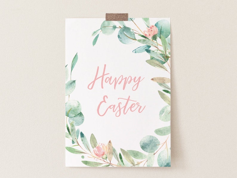Pu&ograve; includere: Un cartello bianco stampabile con una ghirlanda ad acquerello di foglie verdi e fiori rosa. Il testo "Buona Pasqua" &egrave; scritto in corsivo rosa.