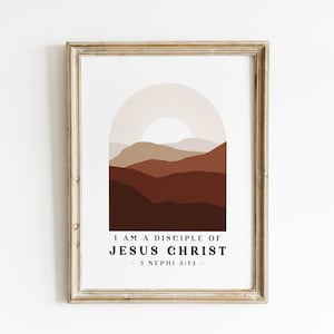 May include: A framed print with a minimalist mountain landscape in shades of brown and beige. The text "I am a disciple of Jesus Christ - 3 Nephi 5:13 -" is printed below the image.