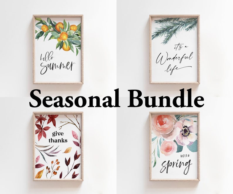 May include: A set of four printable wall art prints featuring watercolour illustrations of seasonal themes. The prints include a summer scene with oranges and leaves, an autumn scene with red and orange leaves, a winter scene with a pine branch, and a spring scene with pink and white flowers. The prints are all framed in a light wood frame and have a white background. The text on the prints reads "hello summer", "give thanks", "it's a wonderful life", and "hello spring".