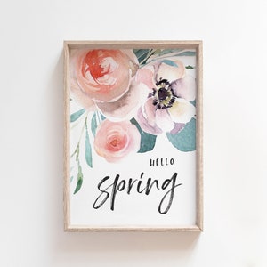May include: A framed print featuring a watercolour painting of pink and purple flowers with green leaves. The text "Hello Spring" is written in black cursive lettering.