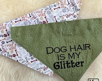 May include: Two triangular pet bandanas. One is white with a repeating pattern of brown and grey dog bones, paw prints, and the words woof, sniff, and bow. The other is olive green with white dots and the black text DOG HAIR IS MY GLITTER.