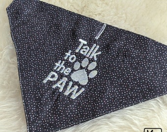 May include: A triangular pet bandana in black fabric with a fine white polka dot pattern. The centre features silver embroidered text that reads I Talk to the PAW, accompanied by a silver embroidered paw print icon centred below the word Talk.