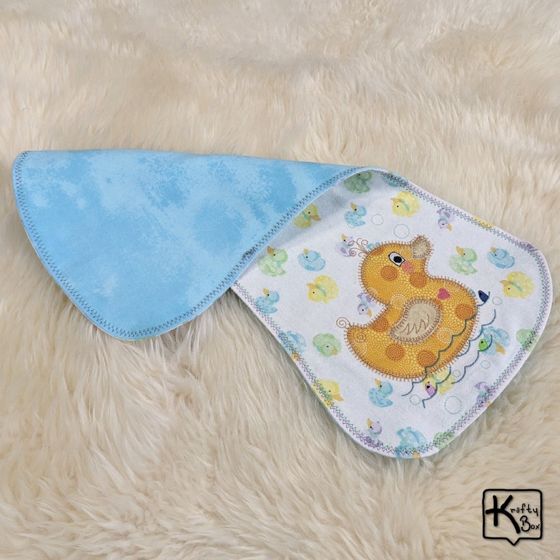 Baby burping cloth made with soft flannel rubber ducky design and accented with an embroidered rubber duck and detail stitching all through the edge.