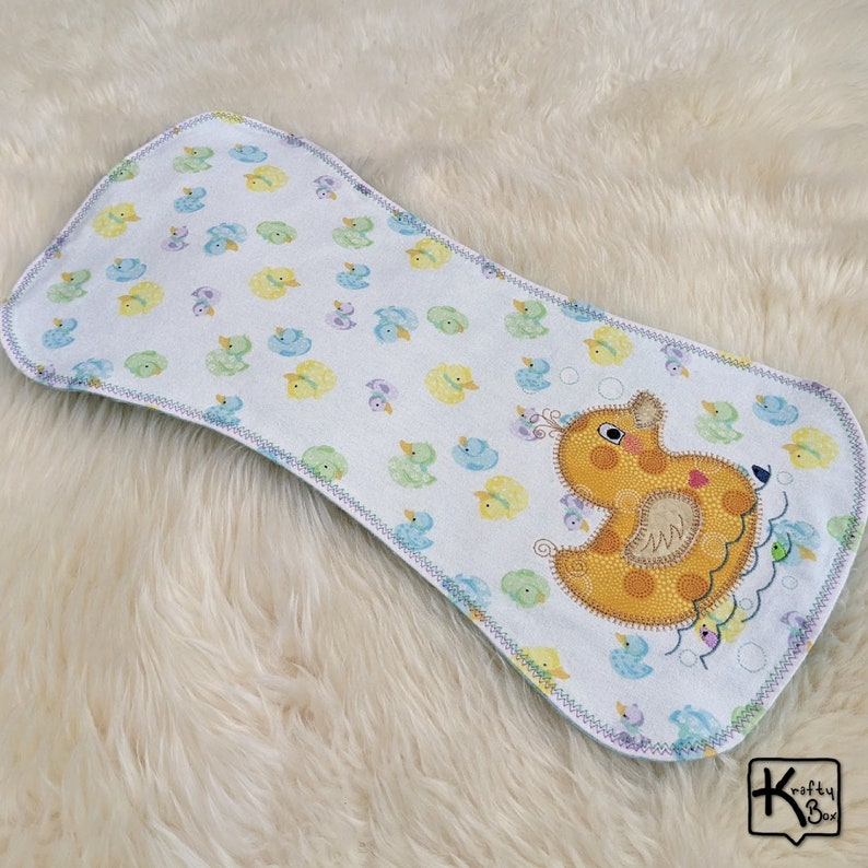 Baby burping cloth made with soft flannel rubber ducky design and accented with an embroidered rubber duck and detail stitching all through the edge.