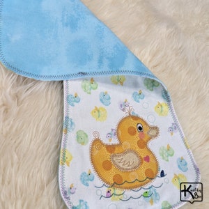 Baby burping cloth made with soft flannel rubber ducky design and accented with an embroidered rubber duck and detail stitching all through the edge.