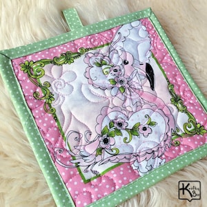 May include: Square quilted potholder featuring a flamingo design. The potholder has a pink polka dot background with a green border. The flamingo is in shades of pink, white, and black, with floral accents and a green frame.
