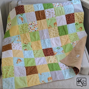 May include: A patchwork quilt featuring a variety of square fabric patterns in shades of green, yellow, blue, and brown. The design includes giraffe illustrations, heart motifs, gingham, and animal print patterns. A solid tan fabric lines the underside.