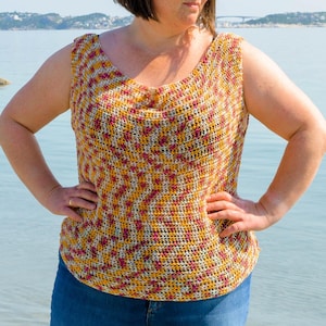 May include: A sleeveless, crocheted top in a vibrant mix of colours, including yellow, white, and magenta. The top has a scoop neckline and a textured, open weave. The garment is paired with blue jeans, creating a casual, summery look.