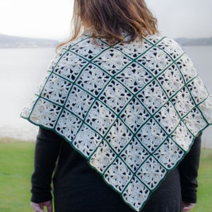May include: A white crocheted shawl with a green border. The shawl is triangular in shape and has a delicate, lacy pattern.
