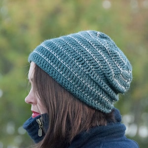 May include: A teal and white striped crocheted beanie hat. The hat is slouchy and has a ribbed texture.