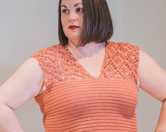 May include: A coral-colored, sleeveless crochet top with a V-neck. The top features a detailed openwork design across the shoulders and a ribbed pattern on the bodice. The handmade garment is a stylish addition to any wardrobe.