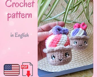 May include: A digital crochet pattern in English for two plush cupcakes. The cupcakes feature light brown bases, white and pink striped tops, purple accents, and embroidered faces with large eyes. Includes a PDF icon and a US flag graphic.