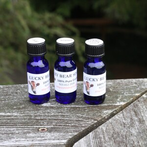 May include: Three small blue glass bottles with white labels. The labels feature a cartoon cow and the text "LUCKY BEAR SO 100% Pure Essential Oil".