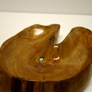 Puede incluir: Un cuenco de madera con una forma natural &uacute;nica y una incrustaci&oacute;n azul claro. El cuenco est&aacute; hecho de una sola pieza de madera y tiene un acabado liso y pulido.