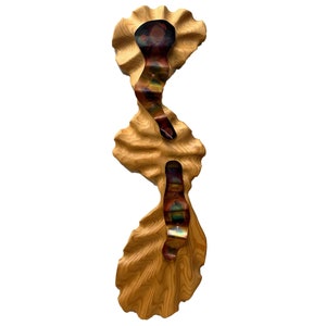 May include: A wooden wall sculpture with a wavy, organic shape. The wood is a light brown color and has a natural grain pattern. The sculpture has three sections with iridescent metal accents.