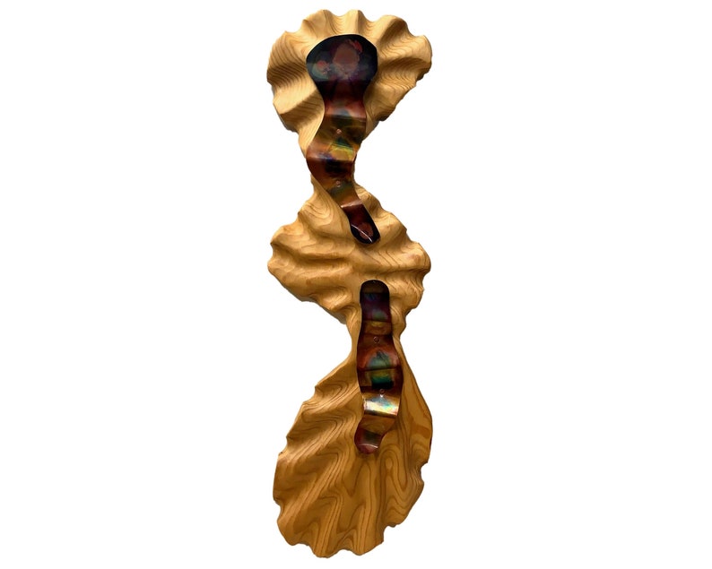May include: A wooden wall sculpture with a wavy, organic shape. The wood is a light brown color and has a natural grain pattern. The sculpture has three sections with iridescent metal accents.