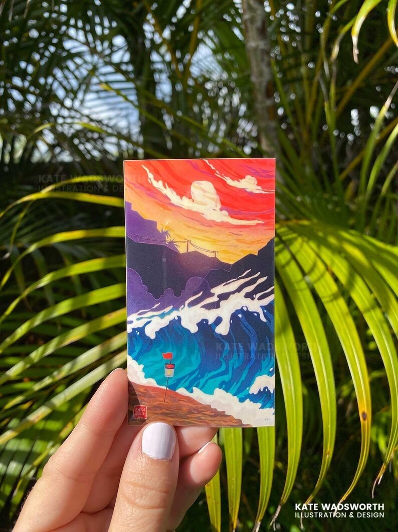 May include: A sticker featuring a colorful illustration of a sunset over a beach with waves crashing on the shore. The sky is a vibrant red and orange with white clouds. The water is a deep blue with white foam. There are two red flags on the beach.