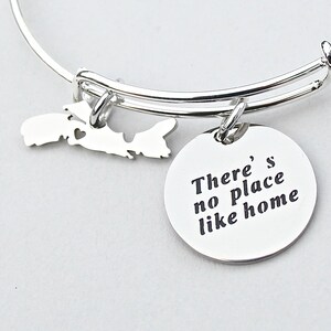 May include: Silver charm bracelet with a charm shaped like Prince Edward Island and a round charm with the text "There's no place like home".