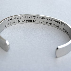 May include: A silver bangle bracelet engraved with the message: "I carried you every second of your life and I will love you for every second of mine."
