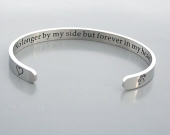 May include: Silver cuff bracelet with the inscription "No longer by my side but forever in my heart". The bracelet has a heart and paw print on each end.